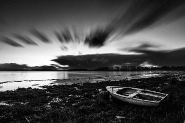 Trasimeno Gölü kıyılarının uzun pozlama manzarası Küçük bir tekne ve hareket eden bulutlarla Umbria, İtalya