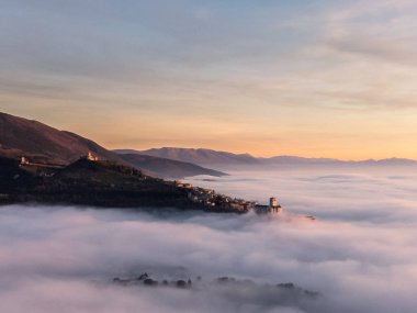 Assisi Umbria İtalya 'nın güneş batarken sis denizi üzerindeki insansız hava aracı görüntüsü