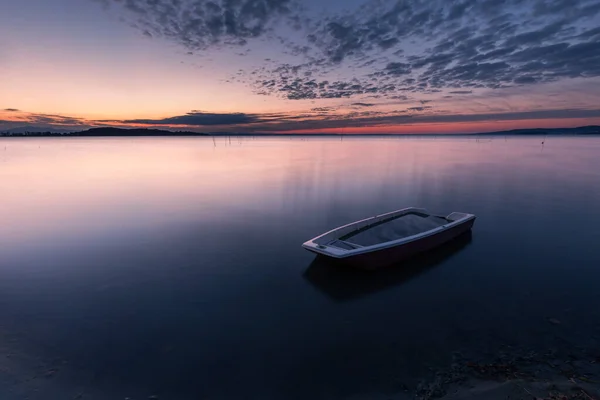 Surrealistische lange uitzicht op de oever van Trasimeno meer Umbrië, Italië met een kleine boot en perfect rustig water — Stockfoto