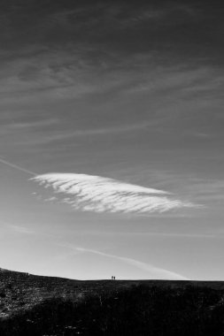 Üzerlerinde bulut olan bir dağın tepesinde iki uzak insan..