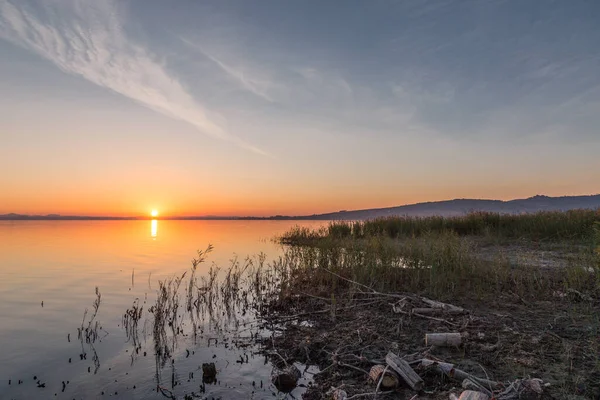 stock image Lake shore at sunset with sun reflecting on water.