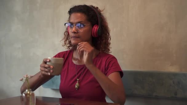 Fiatal nő hallgat podcast és kávézás közben ül asztalnál kávézóban gyógyfürdők.