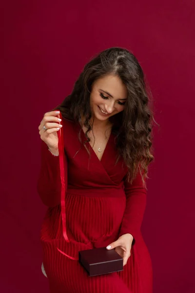 Kırmızılı duygusal kadın çizgili ve gülümseyen bir kutu açtı..