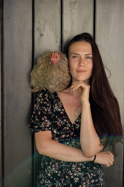 Kumral kadın kameraya poz veriyor, omzunda tavuk var..