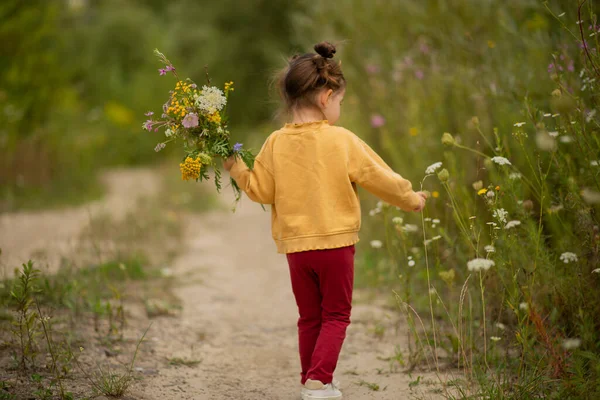 Elinde taze çayır çiçekleri tutan tatlı bir kız..