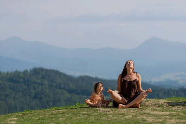 Anne, küçük kızıyla dağlarda nilüfer çiçeği pozu vermiş.