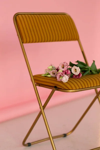 Stüdyoda şık sandalyede pembe çiçekler. Kadınlar günü konsepti. 