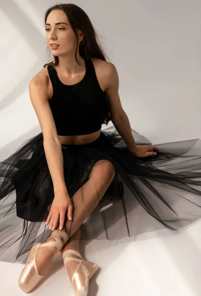Mooie ballerina in zwarte jurk zittend op de vloer — Stockfoto