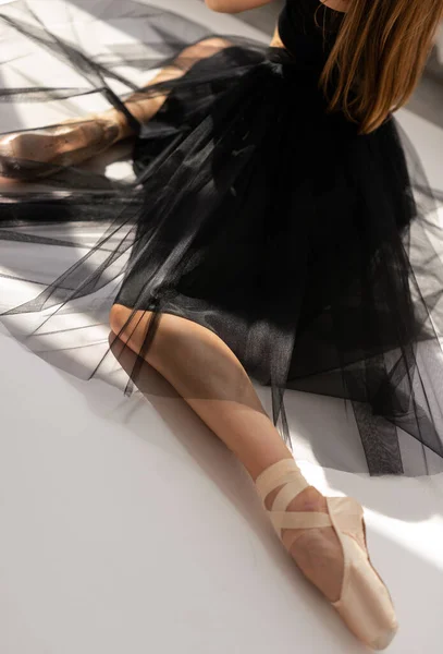 Skörd av ballerina bär svart klänning sittande på golvet. — Stockfoto