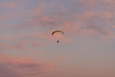 Aerial view on aeroplane in rose orange sunset sky. Airplane pilot doing rounded circle in sky in sunrise. Concept of adrenaline air sport or extreme hobby.