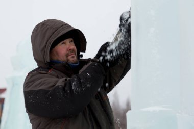 Heykeltıraş, buzdan bir heykeli Noel için keskiyle kesiyor.