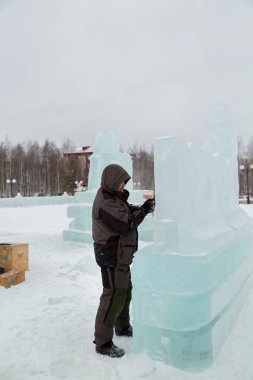 Heykeltıraş, buzdan bir heykeli Noel için keskiyle kesiyor.