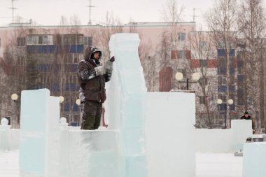 Heykeltıraş, buzdan bir heykeli Noel için keskiyle kesiyor.