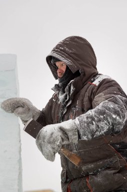 Heykeltıraş, buzdan bir heykeli Noel için keskiyle kesiyor.