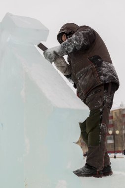 Heykeltıraş, buzdan bir heykeli Noel için keskiyle kesiyor.