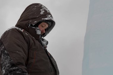 Kar maskeli bir işçi ve kafasında da bir kapüşon var.