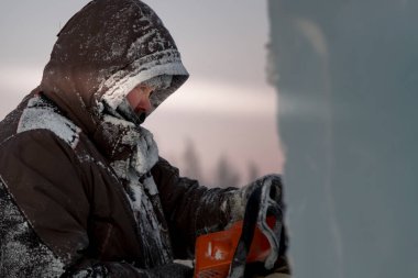 Heykeltıraş Noel için buz kalıbından bir buz heykeli kesiyor.