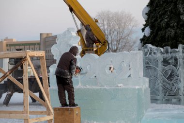 Heykeltıraş Noel için buz kalıbından bir buz heykeli kesiyor.