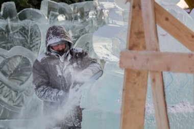 Heykeltıraş Noel için buz kalıbından bir buz heykeli kesiyor.