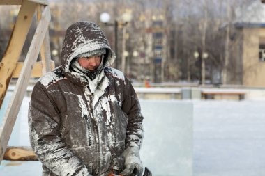 İş yerinde kar maskesi takan ve başlıklı bir işçi.