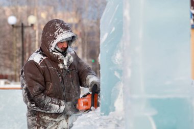 Heykeltıraş Noel için buz kalıbından bir buz heykeli kesiyor.