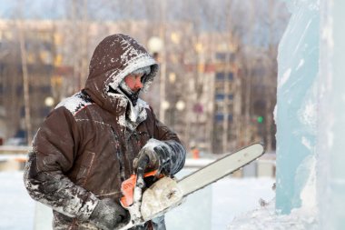 Heykeltıraş Noel için buz kalıbından bir buz heykeli kesiyor.