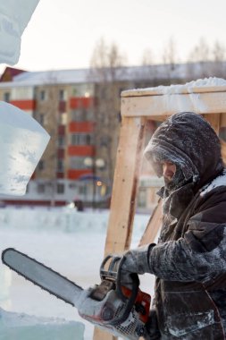 Heykeltıraş Noel için buz kalıbından bir buz heykeli kesiyor.