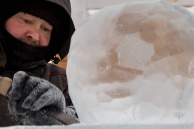Heykeltıraş, buzdan bir heykeli Noel için keskiyle kesiyor.