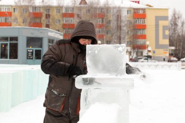 İş yerinde kar maskesi takan ve başlıklı bir işçi.