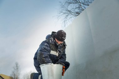 Buz kasabasının toplanma yerinde elinde kova olan bir işçi.