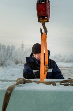 Ceketli ve siyah şapkalı işçi derleyicisi buz bloklarını boşaltıyor