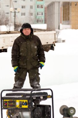 Kış üniformalı bir işçi, buz kasabasının inşaat alanında yürüyor.