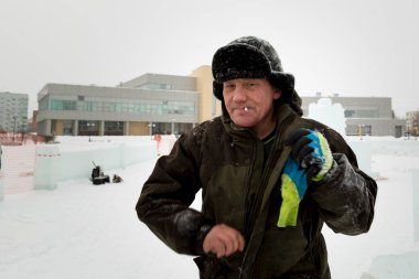 Kış üniformalı bir işçi, buz kasabasının inşaat alanında yürüyor.