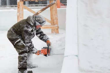 Heykeltıraş, buzdan bir buz figürünü Noel için elektrikli testere ile kesiyor.