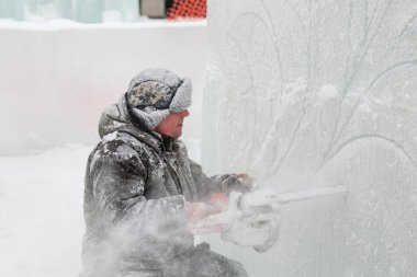 Heykeltıraş, buzdan bir buz figürünü Noel için elektrikli testere ile kesiyor.