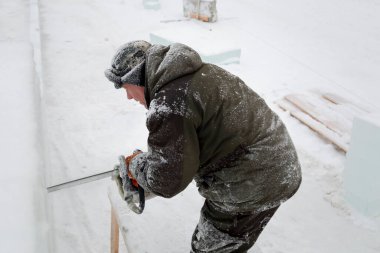 Heykeltıraş, buzdan bir buz figürünü Noel için elektrikli testere ile kesiyor.