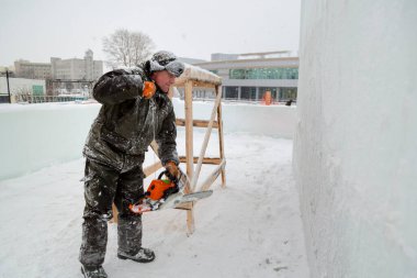 Kurucu, testereyi buz kasabasının montaj sahasında çalıştırır.