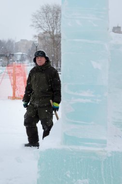 Kış üniformalı bir işçi, buz kasabasının inşaat alanında yürüyor.