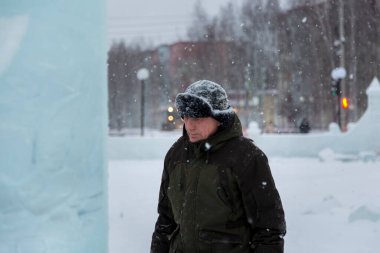 Kış üniformalı bir işçi, buz kasabasının inşaat alanında yürüyor.