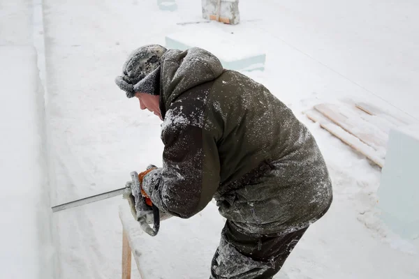 Heykeltıraş, buzdan bir buz figürünü Noel için elektrikli testere ile kesiyor.