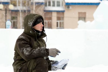 Yeşil kapüşonlu ceketli bir işçi bir kağıt parçasındaki diyagramı inceliyor.