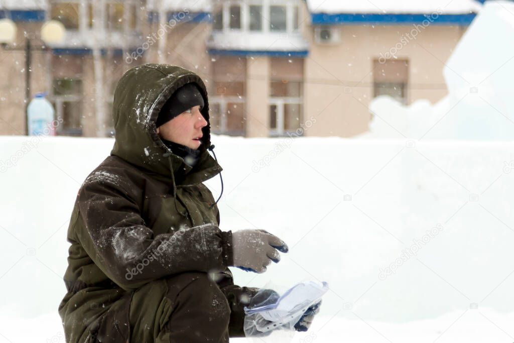 A worker in a green hooded jacket examines a diagram on a piece of paper
