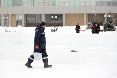 Buz kasabasının toplanma yerinde elinde kova olan bir işçi.