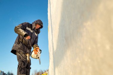 Elinde testereyle buz panelinin kurulumunu yapan bir işçi.