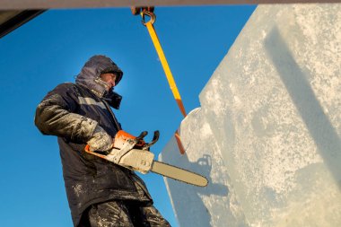 Elinde testereyle buz panelinin kurulumunu yapan bir işçi.