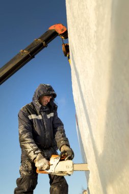 Elinde testereyle buz panelinin kurulumunu yapan bir işçi.