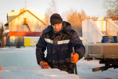 Elinde levyeyle buz kasabasının inşaat alanında çalışan bir işçi.