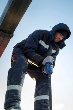 Buz kasabasında metal bir levyeyle buz bloğunu hareket ettiren bir işçinin portresi