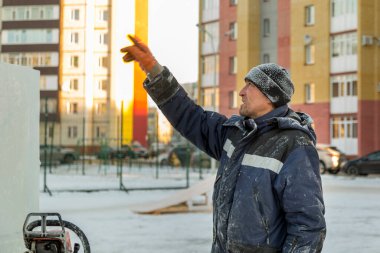Kafasında siyah örgü şapkalı mavi ceketli bir tesisatçının portresi.
