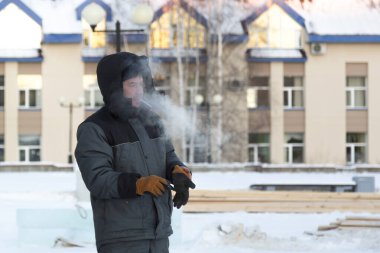 Kafasında başlığı olan, kışlık takım elbiseli bir müteahhit portresi.